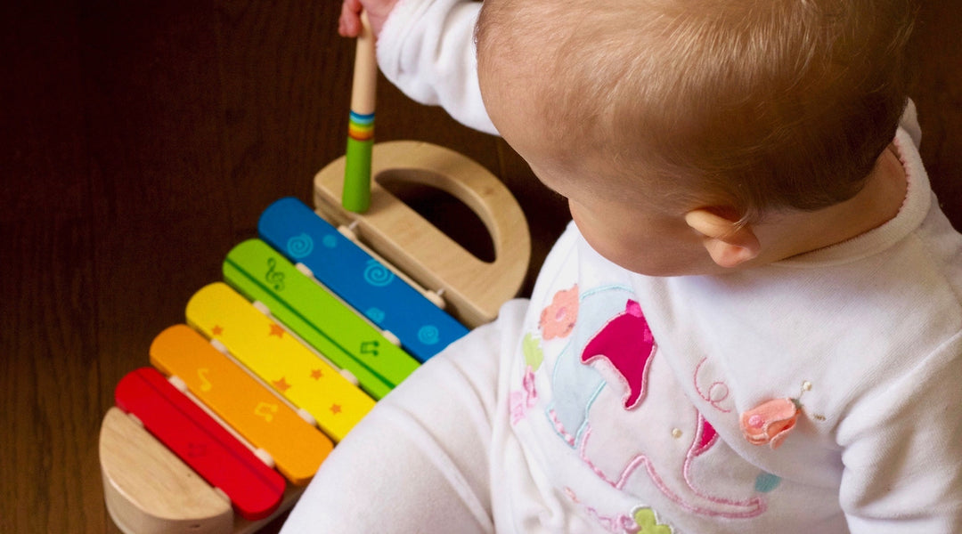 a baby playing with a colorful xylophone