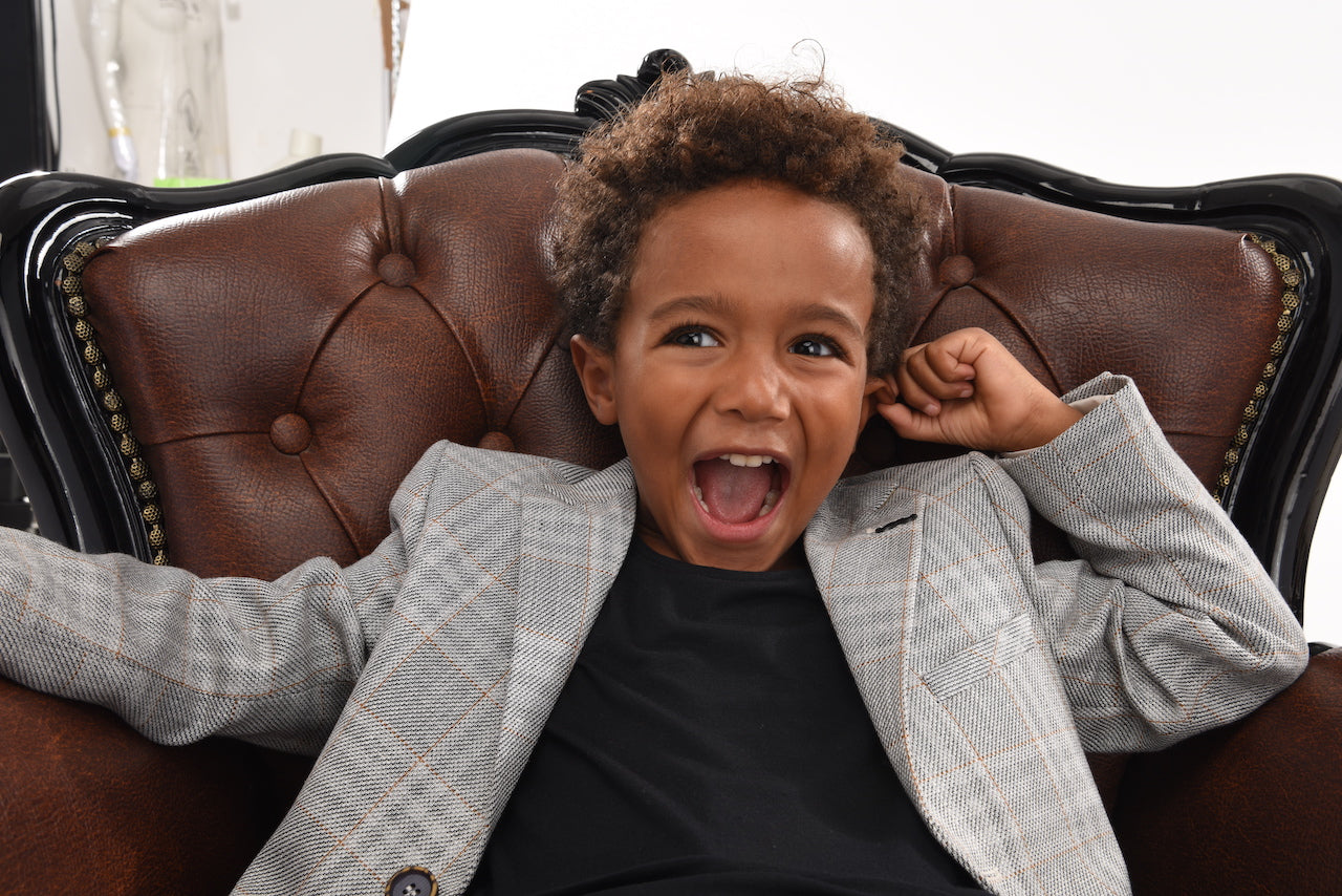 boy wearing suit laughing on a chair